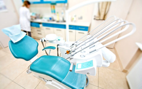 Professional Dentist tools and chair in the dental office. Dental Hygiene and Health conceptual image.